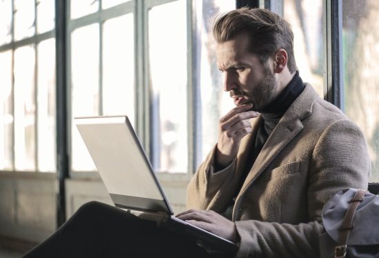 Man looking at his grey laptop looking confused